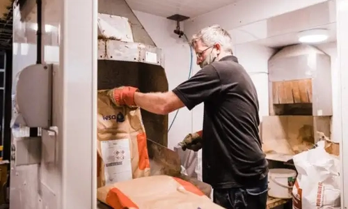 A man  wearing gloves removing a bag from a machine